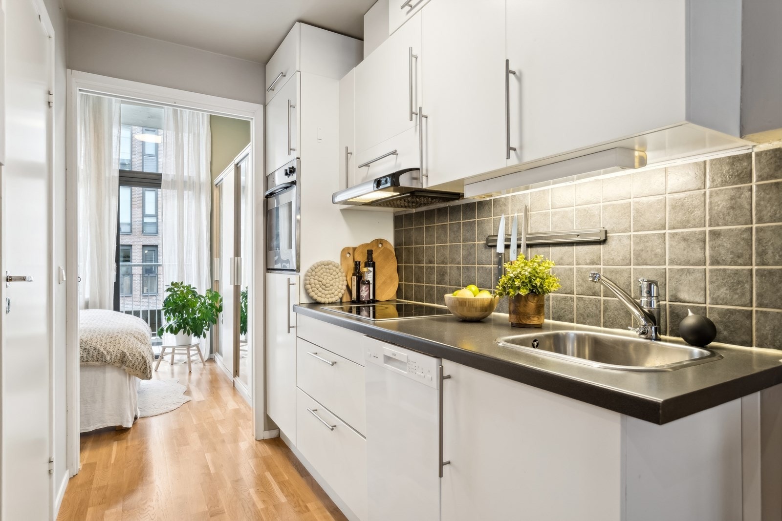 Lyst kjøkken med flis over benkeplaten. Kjøkkeninnredningen har malte fronter uten profil og laminert benkeplate. Galleribilde