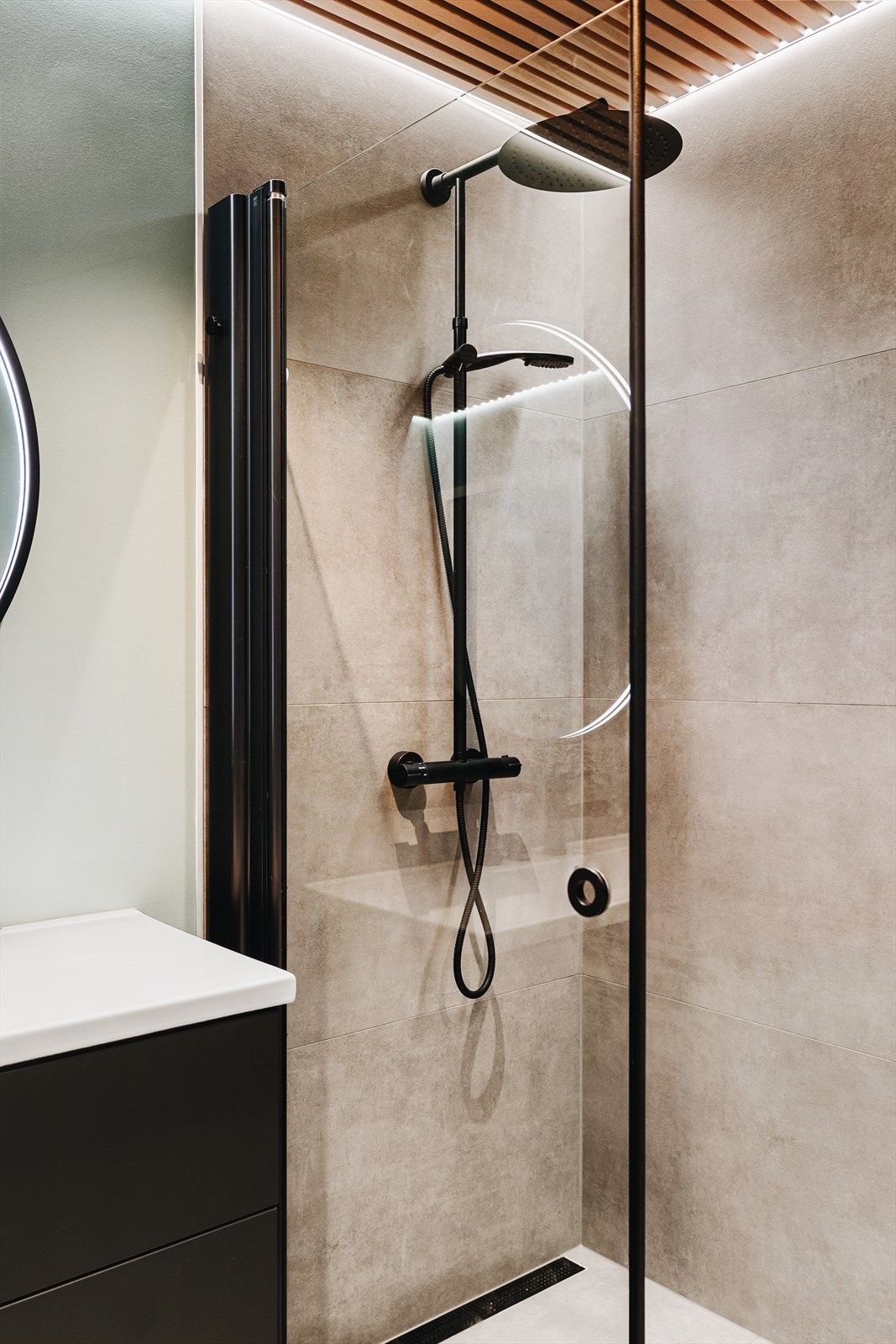 Separat badekar og romslig dusjhjørne. Pen skillevegg i glass, og lekkert avlangt sluk i enden på gulv. Alt møblement er nydelig i sorte og hvite detaljer. Galleribilde