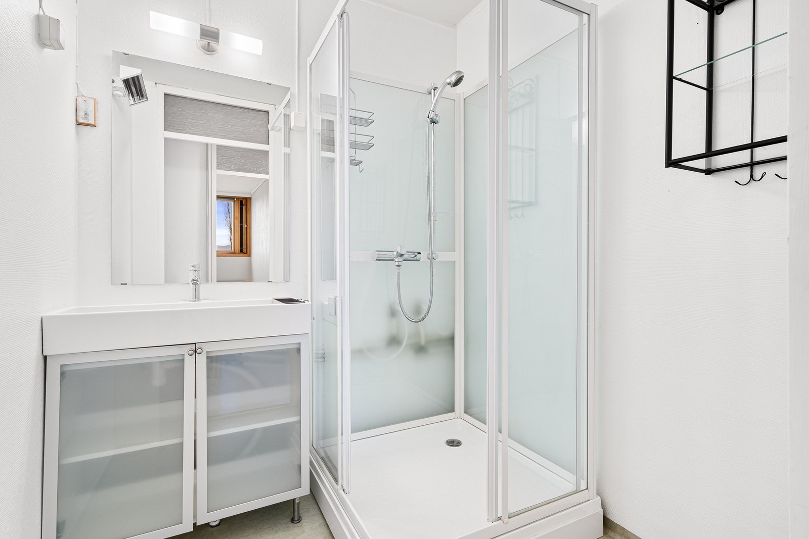 Badet er utstyrt med dusjkabinett, servant i skap og reflektorovn. Galleribilde