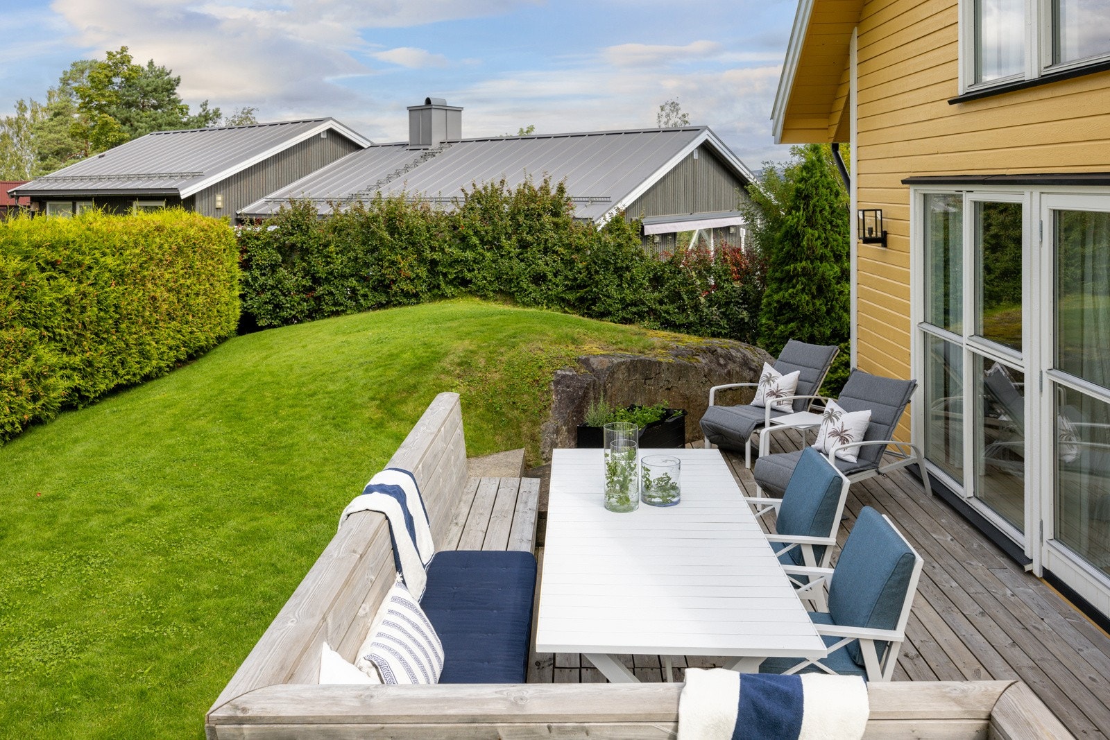 Terrassen har terrassebord på gulv og plassbygde sittebenker med plass til et spisebord. Galleribilde