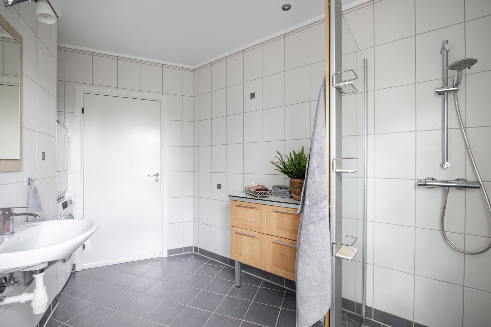 Baderommet er utstyrt med vegghengt servant med speil og belysning over, dusjhjørne med glassvegg og vegghengt toalett. Galleribilde