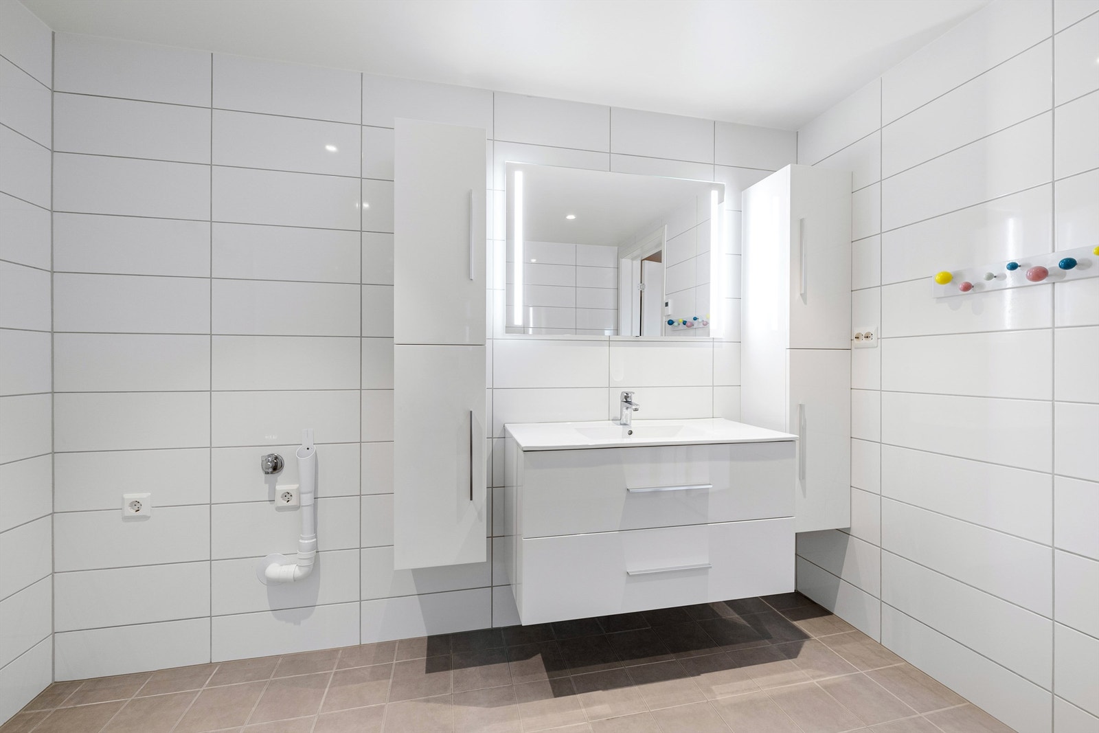 Innredning med ovenpåliggende servant med armatur. Speil med sidelys. Vegghengt baderomsmøbel. Galleribilde