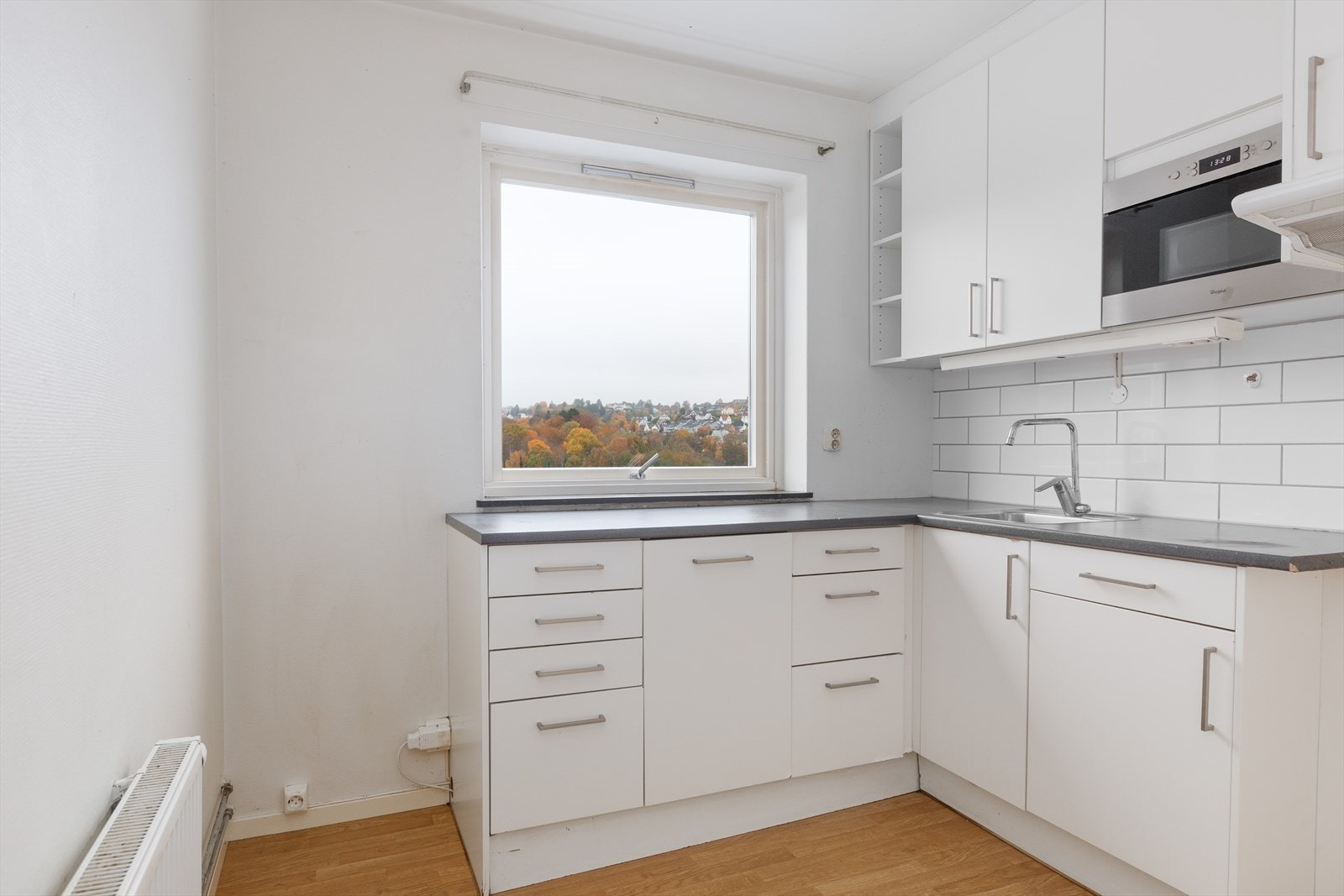 Eldre kjøkkeninnredning med slette skapfronter og integrert mikrobølgeovn Galleribilde