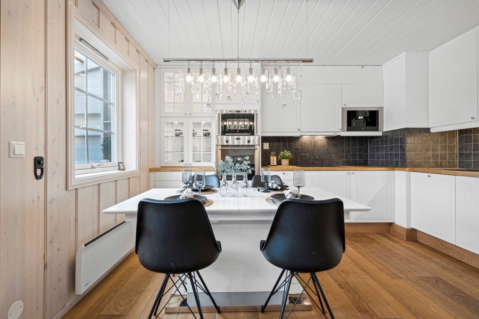 Kjøkkenet har innebygd stekeovn, mikrobølgeovn og kaffemaskin i høyskap. Integrert oppvaskmaskin og kjøl-fryseskap, fliser over benk, og ventilator over komfyr Galleribilde