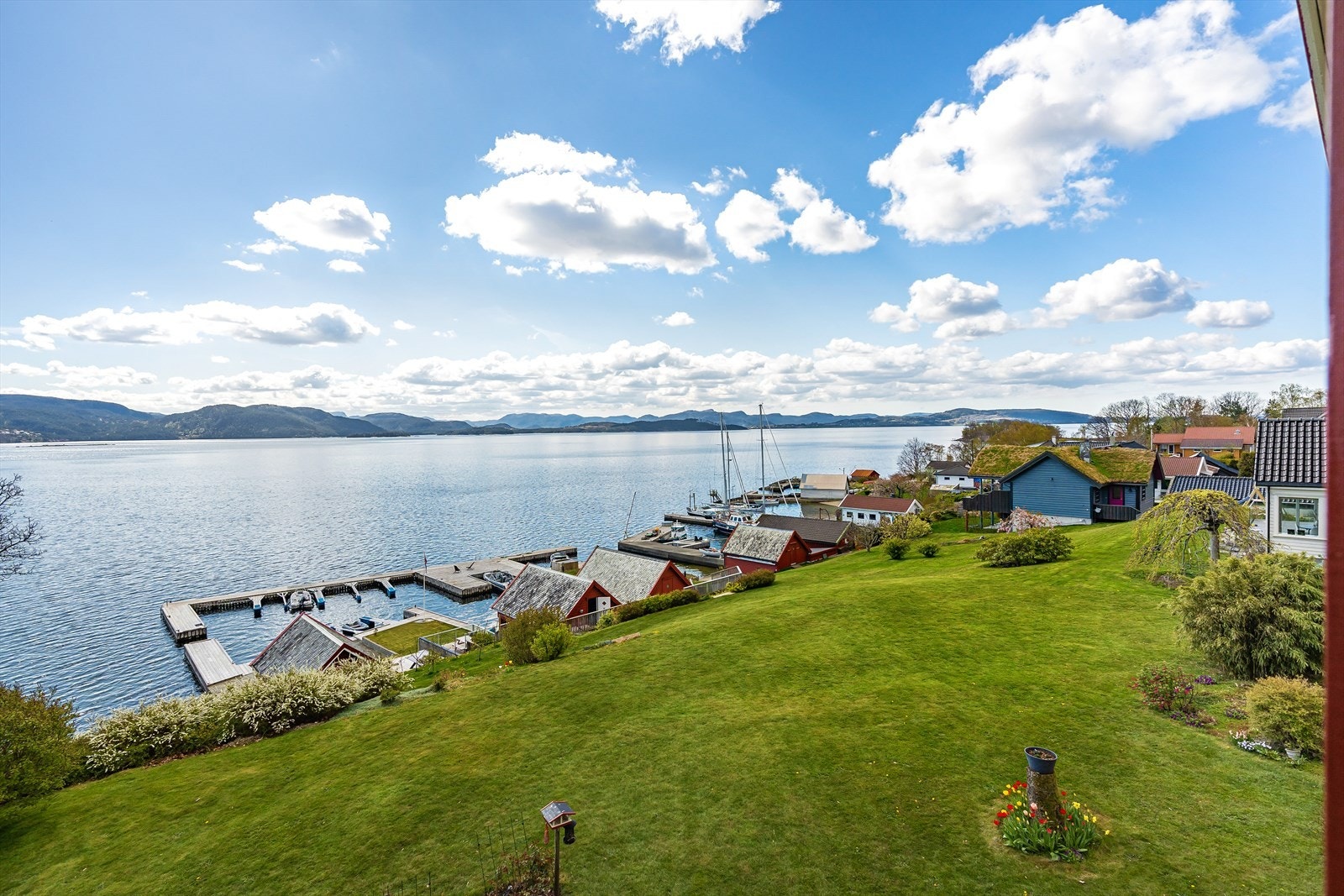 Stor og flott plen som strekker seg fra boligen og ned til sjøen hvor man har få skritt ned til eget naust, molo og badestrand Galleribilde