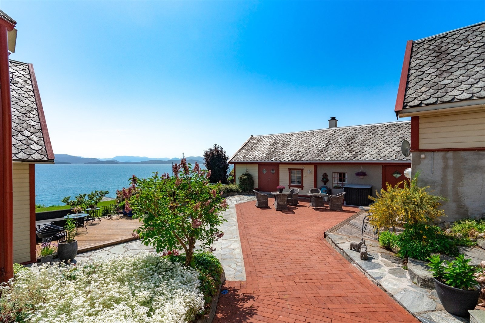 Eiendommen er meget velstelt og pent opparbeidet med beplantning, plattinger og steinheller Galleribilde