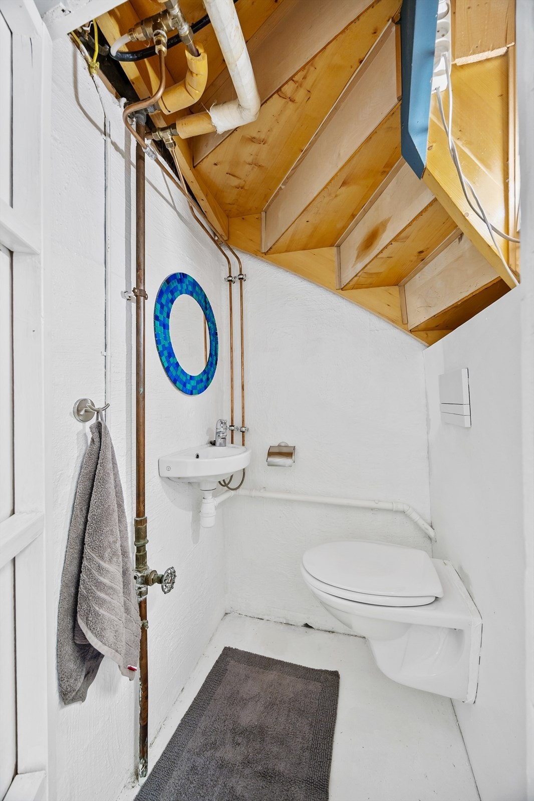 Separat wc-rom innredet med vegghengt wc og enkel servant. Det er malt betonggulv og malte veggplater Galleribilde