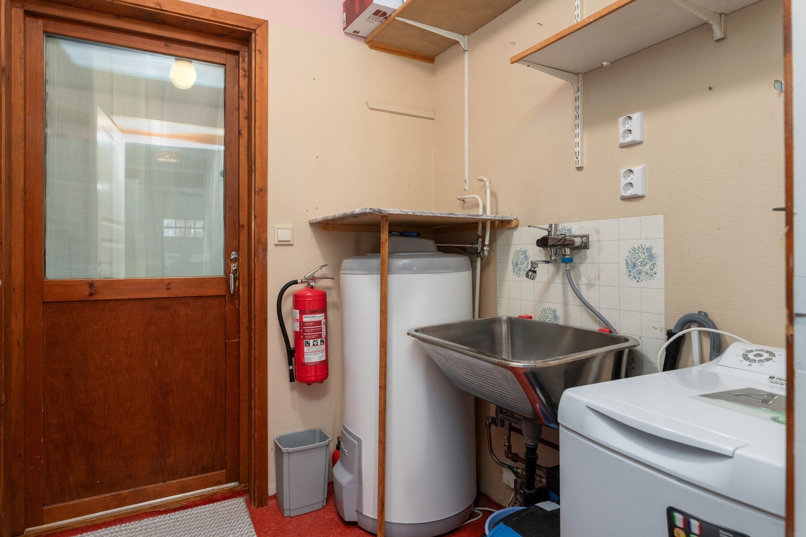 Praktisk separat vaskerom med opplegg for vaskemaskin og skyllekar i stål. Fra rommet er det utgang til boden. Galleribilde