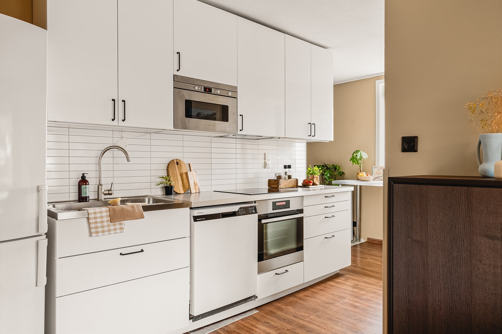 Kjøkkenet inneholder innredning med slette fronter, laminat benkeplate, stål oppvaskkum og ventilator Galleribilde