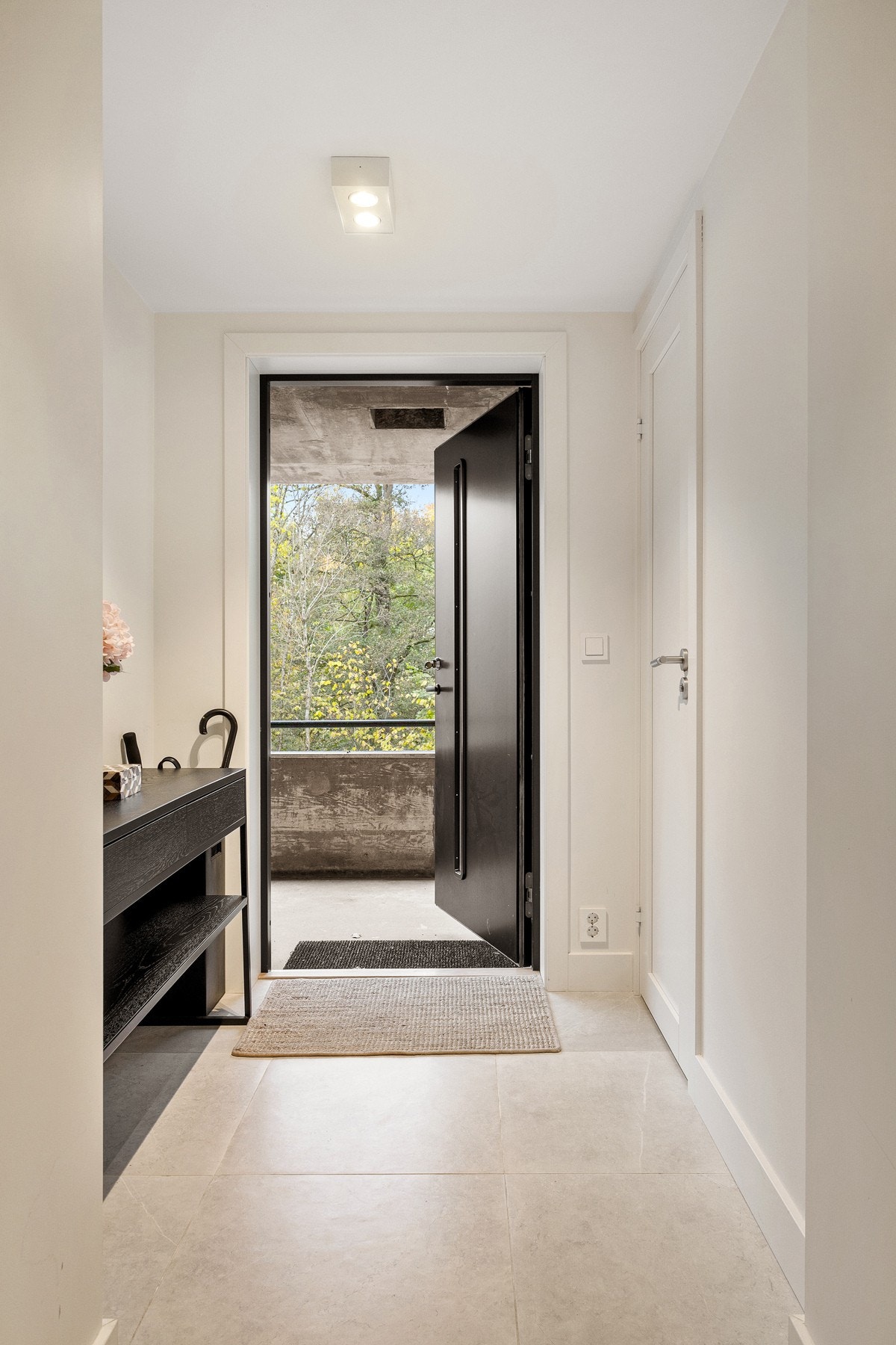 Huset har et overbygd inngangsparti med sort ytterdør, og vel innenfor døra møtes man av en innbydende entré med store, lysegrå gulvfliser. Galleribilde