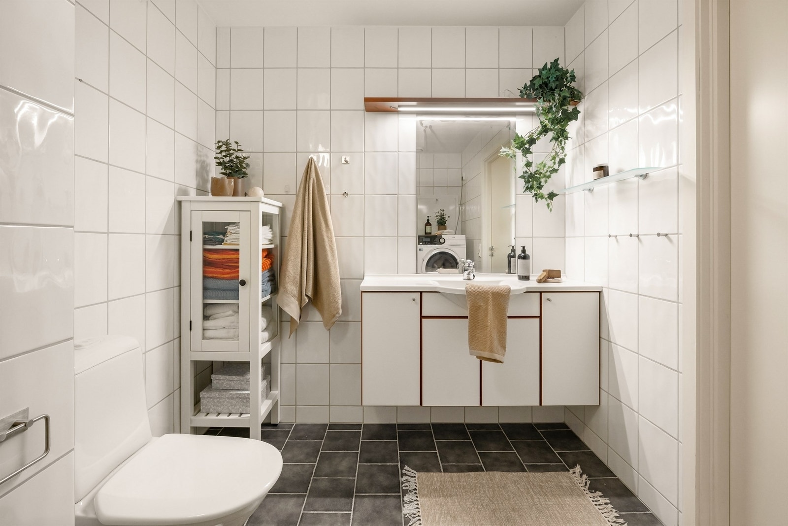 Helfliset baderom med vegghengt klosett, opplegg for vaske og tørketrommel Galleribilde