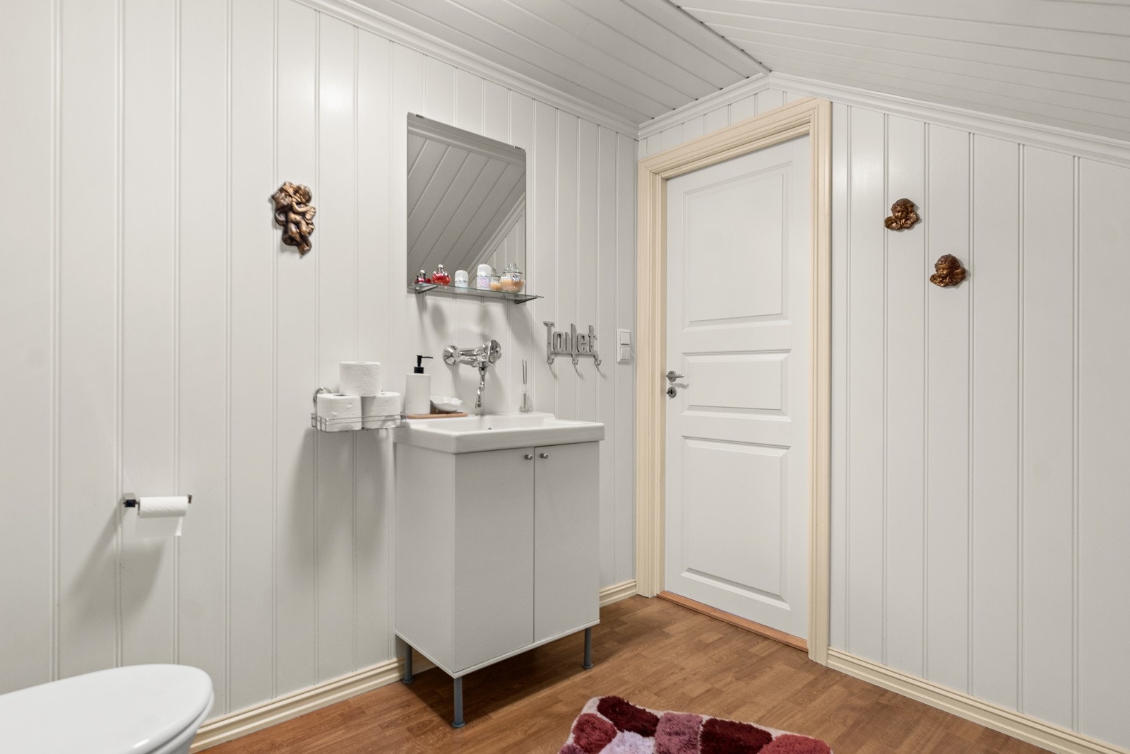 Toalettrom med laminat på gulv og panelplater på vegger. Galleribilde