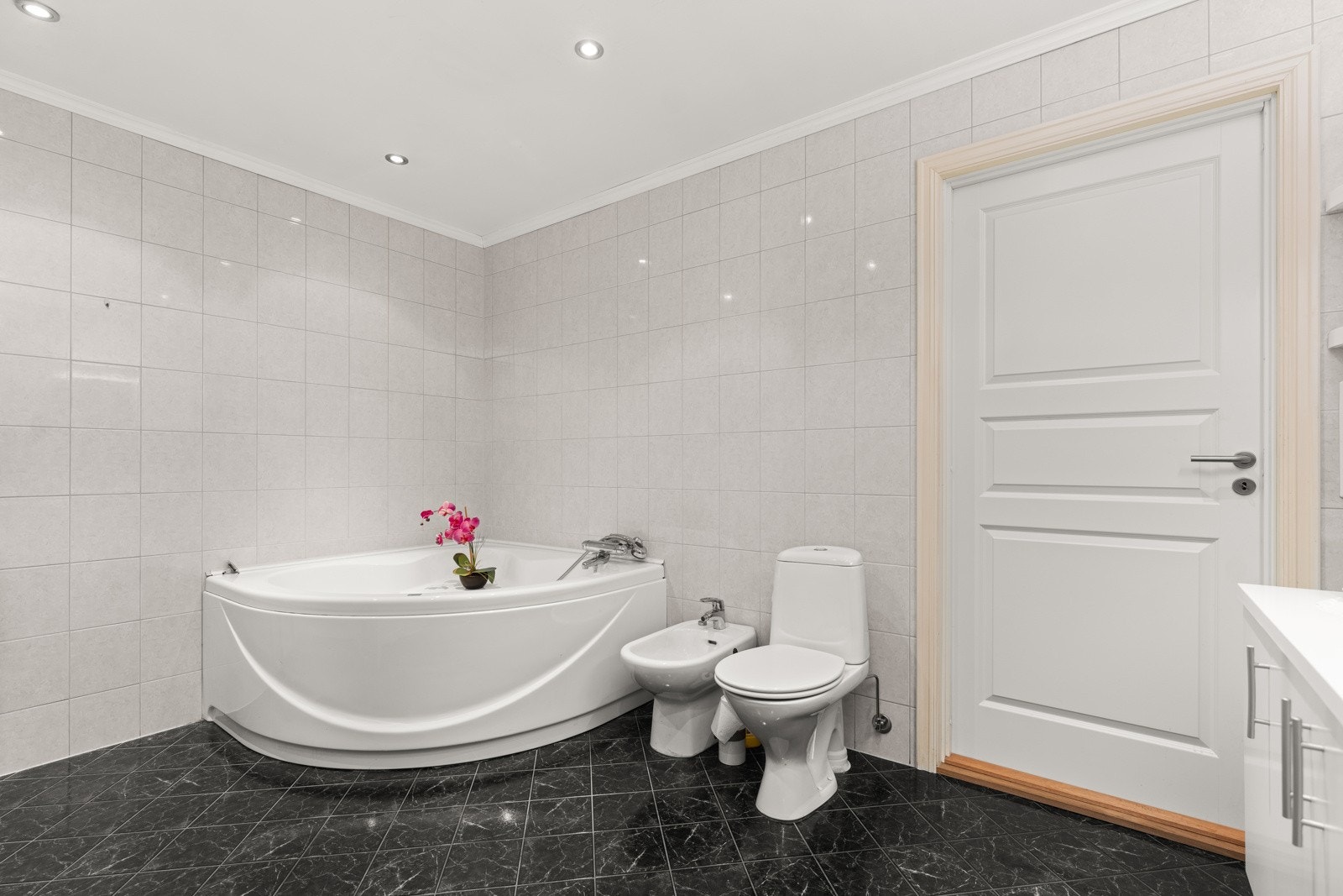 Badet er flislagt med varmekabler på gulv og spotter i tak. Galleribilde
