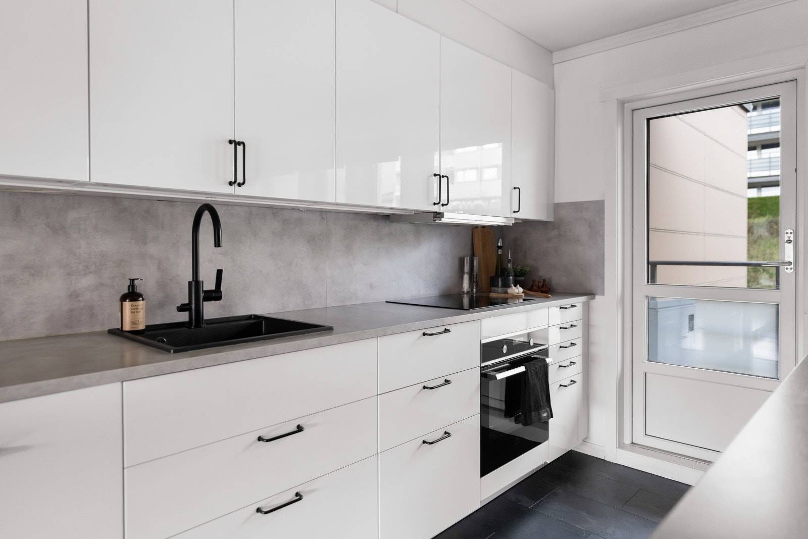 Stilren kjøkkeninnredning fra 2019 med slette fronter og benkeplater av laminat med nedfelt oppvaskkum i kompositt. Galleribilde