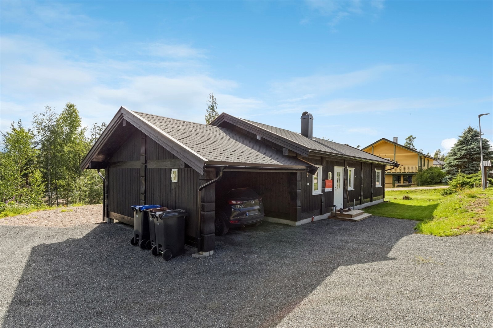 Inngangsparti til boligen med carport utbygget som en forlengelse av huset i gavl. Galleribilde