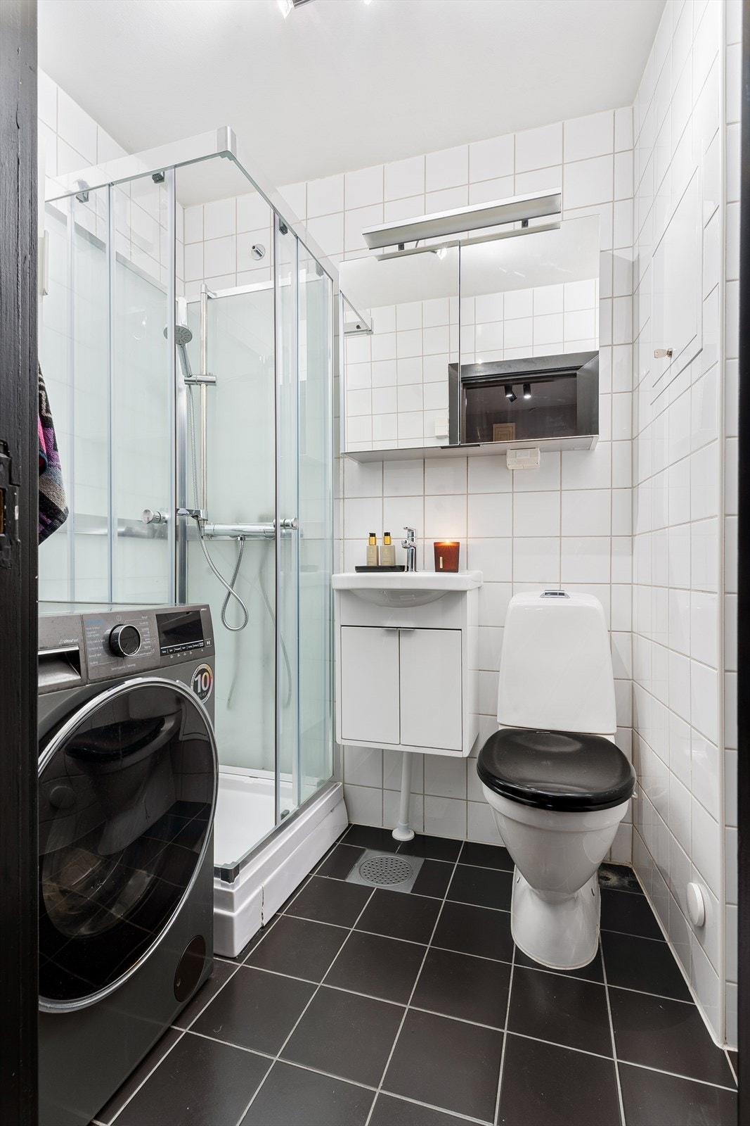 Badet er innredet med dusjkabinett, servant, klosett, overskap med speilfronter og opplegg for vaskemaskin. Galleribilde