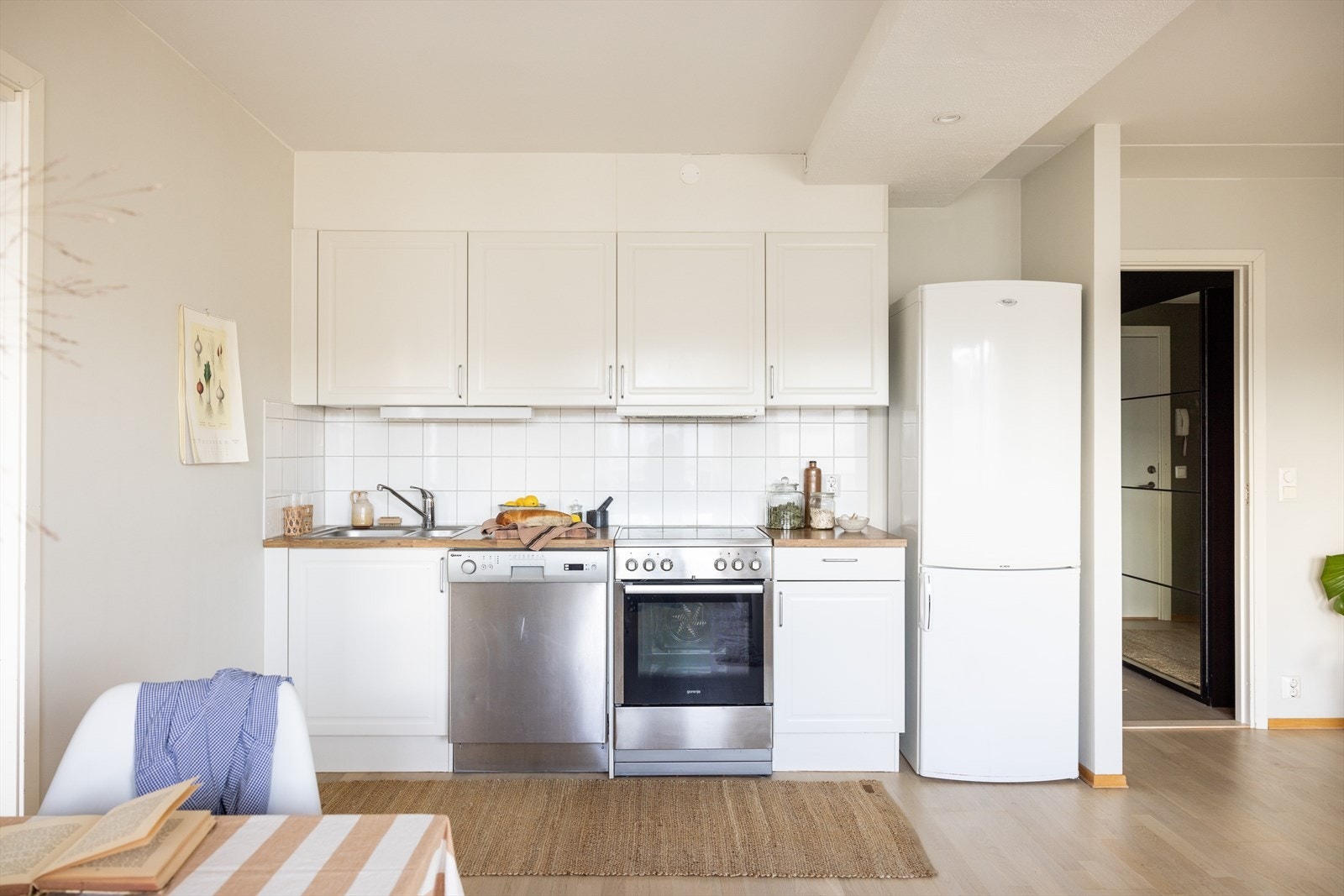 Kjøkkeninnredning med profilerte fronter, fliser på vegg over benkeskap og belysning under overskap Galleribilde