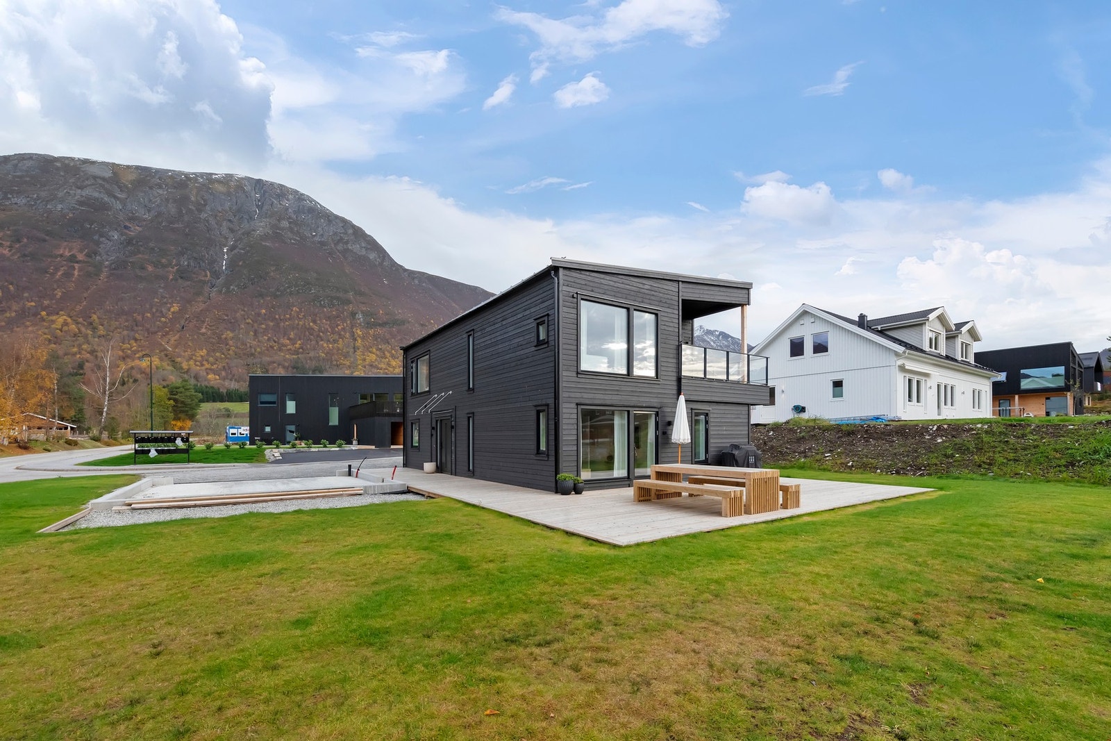 Stor og romslig tomt opparbeidet med plen, prydbusker og hekk mot vei Galleribilde