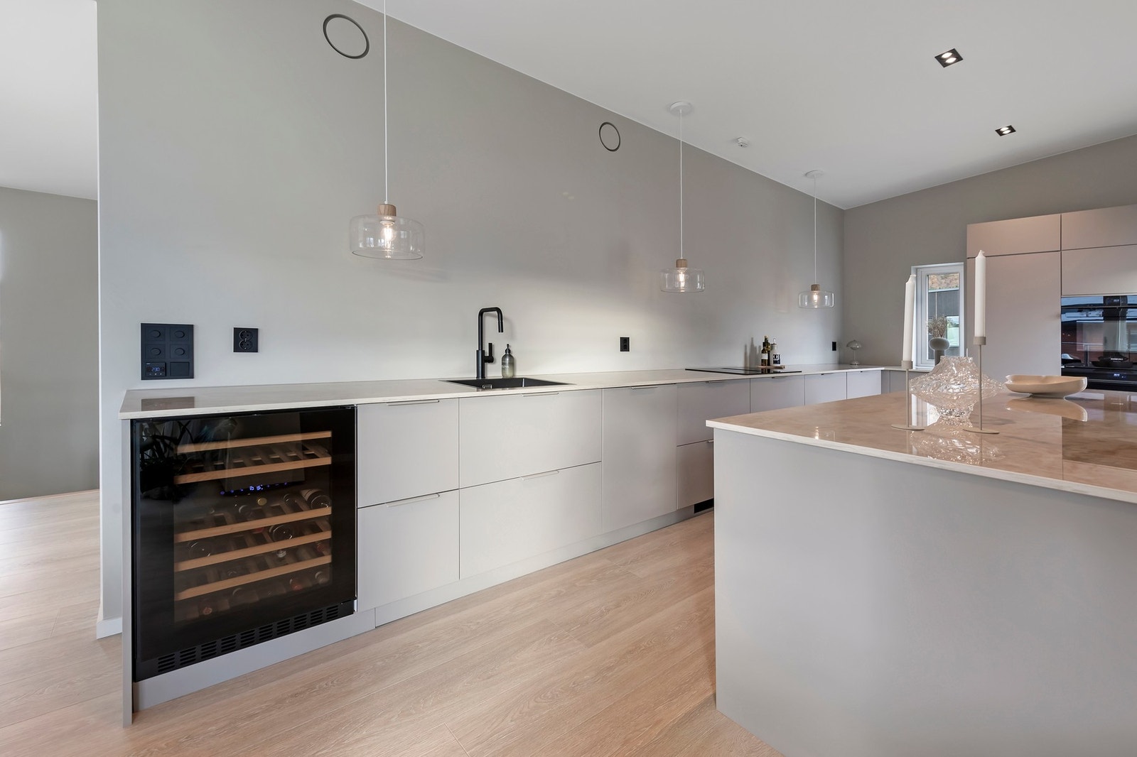 Lys kjøkkeninnredning fra Kvik med glatte fronter og keramisk benkeplate Galleribilde