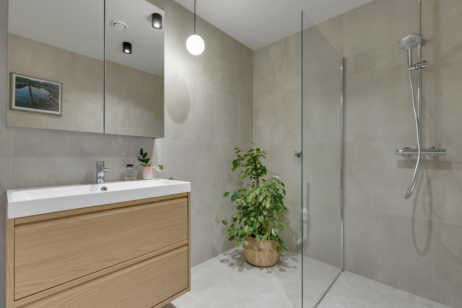 I hjørnet av badet har du opplegg for vaskemaskin. I tillegg er badet utstyrt med plassbesparende dusjdører av glass, vegghengt WC, speilskap og servantløsning med skuffer. Galleribilde