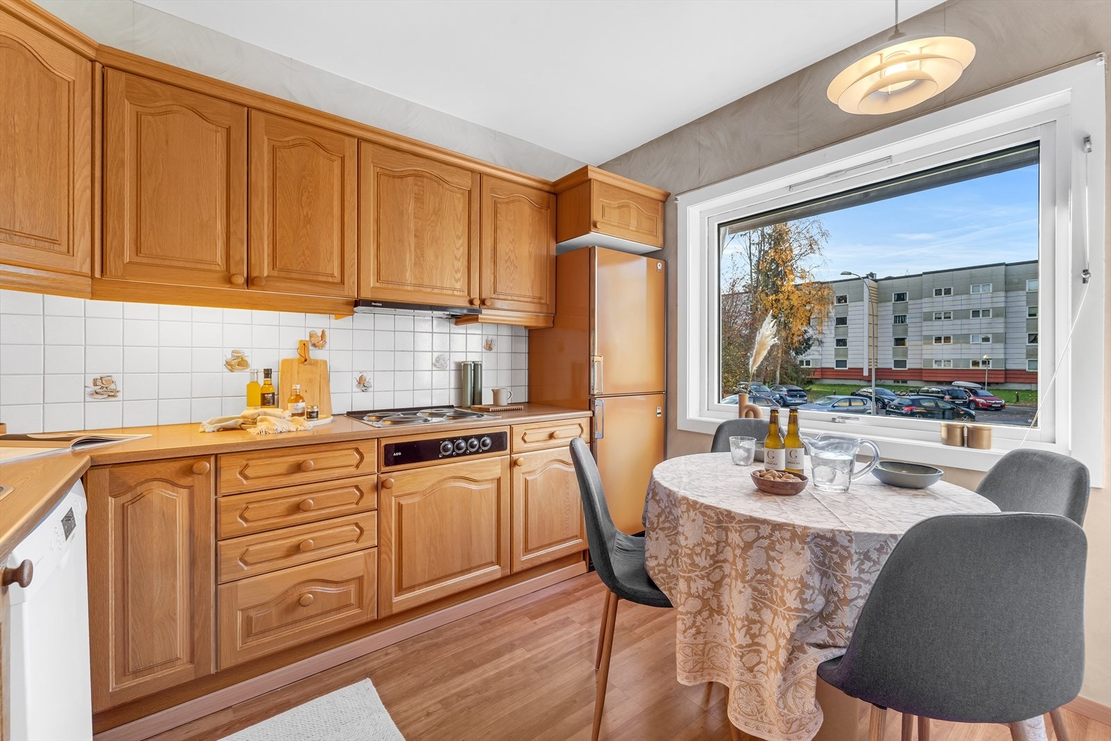 Kjøkken med laminat på gulv med varmefolie, tapet på vegger og malt tak. Kjøkkeninnredning med eikefronter, laminat benkeplate med fliser over, ventilator, opplegg for oppvaskmaskin og integrerte hvitevarer som stekeovn og koketopp. Galleribilde