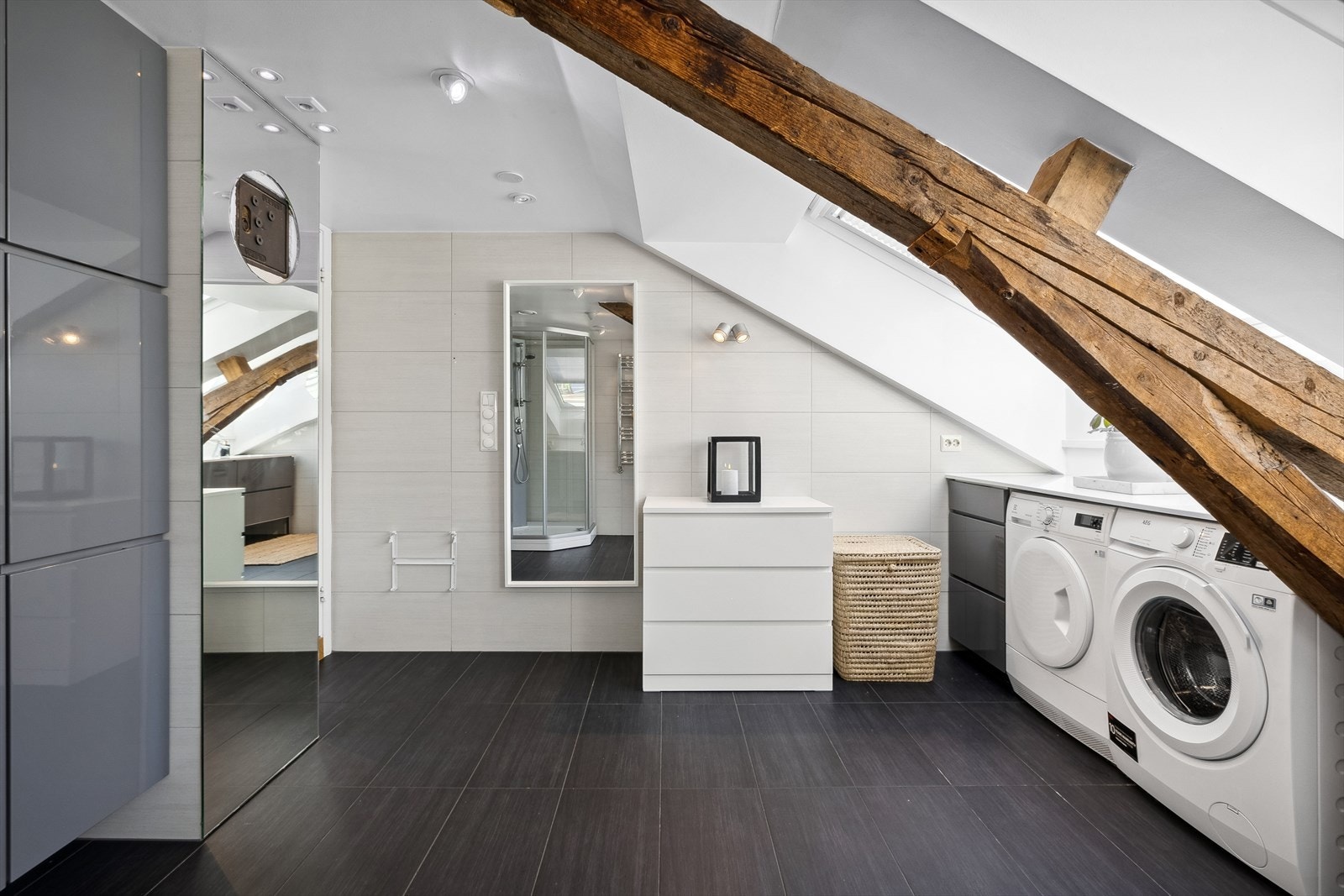 Badet er innredet med veggmontert toalett, dusjkabinett, innredning og opplegg for vaskemaskin. Galleribilde