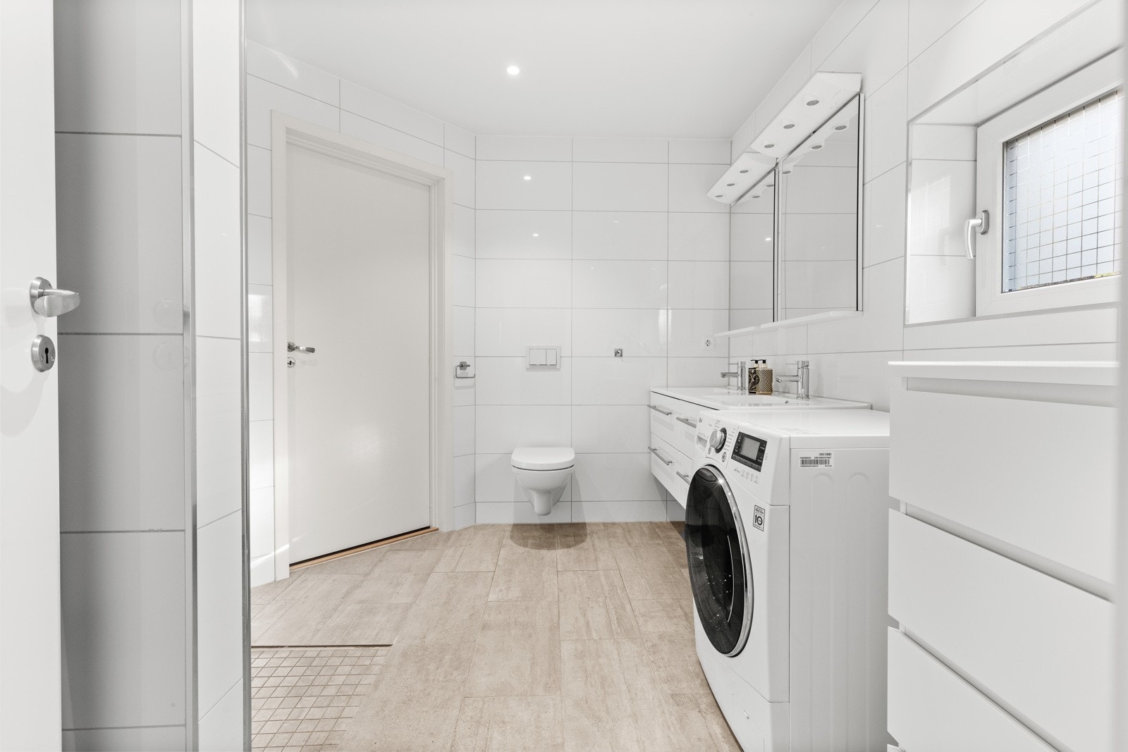 På badet er det dobbel servant, servantskap, veggmontert wc, dusjhjørne med innfellbare dører og opplegg for vaskemaskin Galleribilde