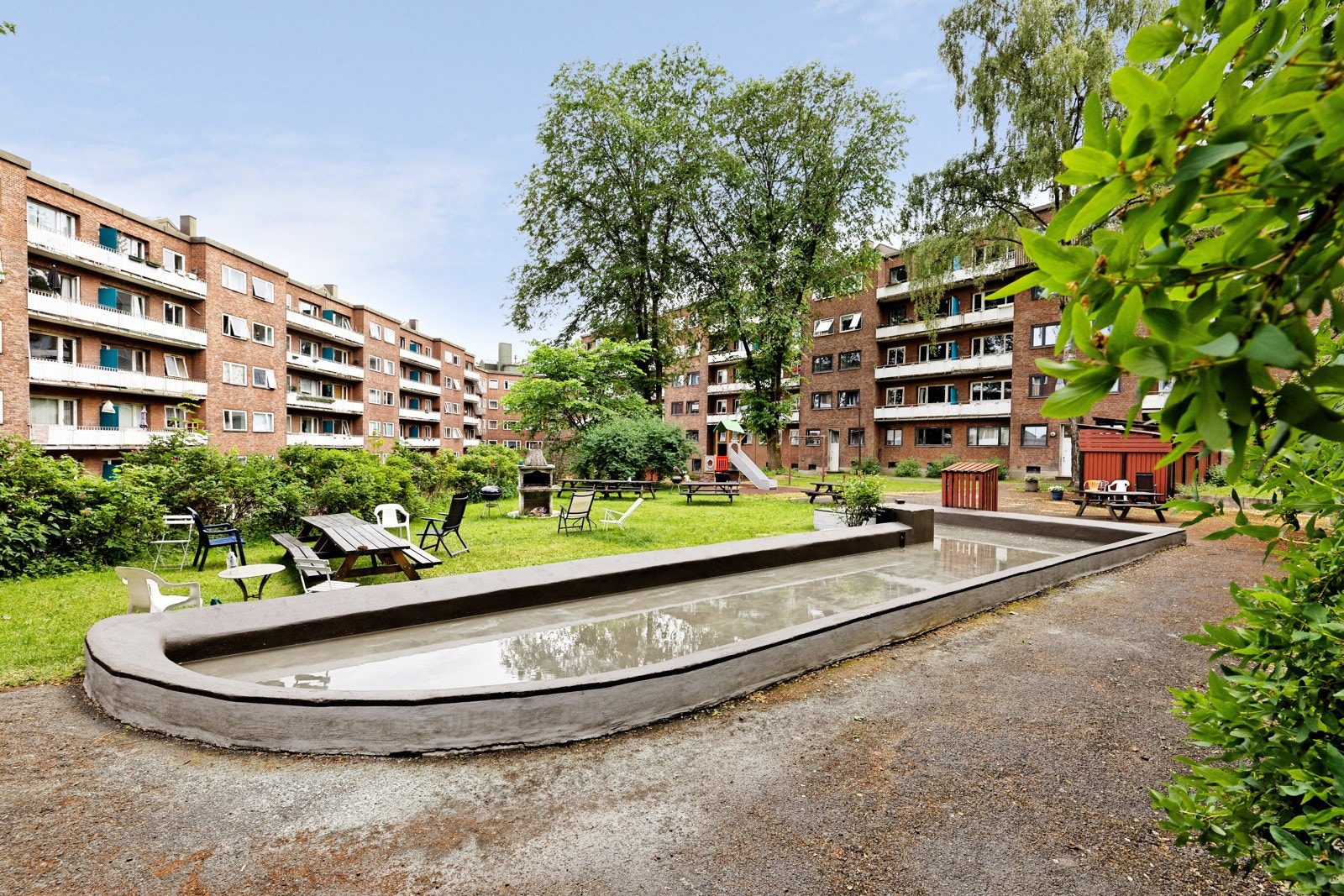 Hyggelig bakgård med sittegrupper og utegrill, vannspeil samt diverse busker og beplantinger mm. Galleribilde