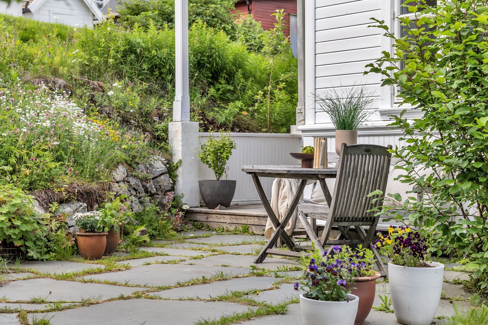 Tomten er nydelig arrondert med skiferlagte adkomster, plenarealer, sittegrupper og prydvekster Galleribilde