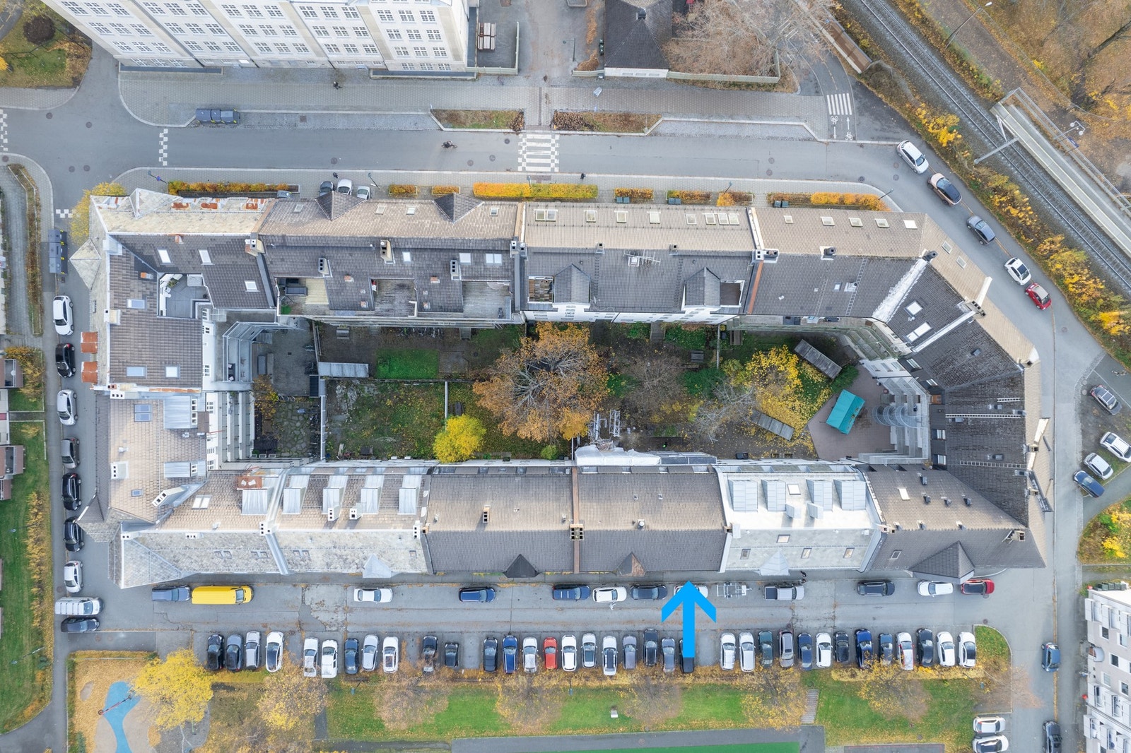 Dronebilde av bygården. Bygården har adressene Ladeveien og Gardemoens gate. Leilighetens beliggenhet er markert med blå pil. Galleribilde