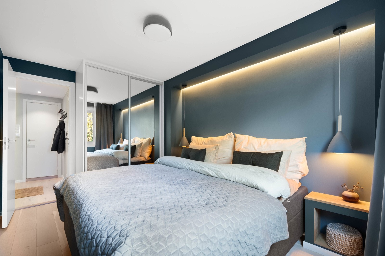 Sengen og nattbordene er plassert i en egen nisje, rammet inn med elegant belysning Galleribilde