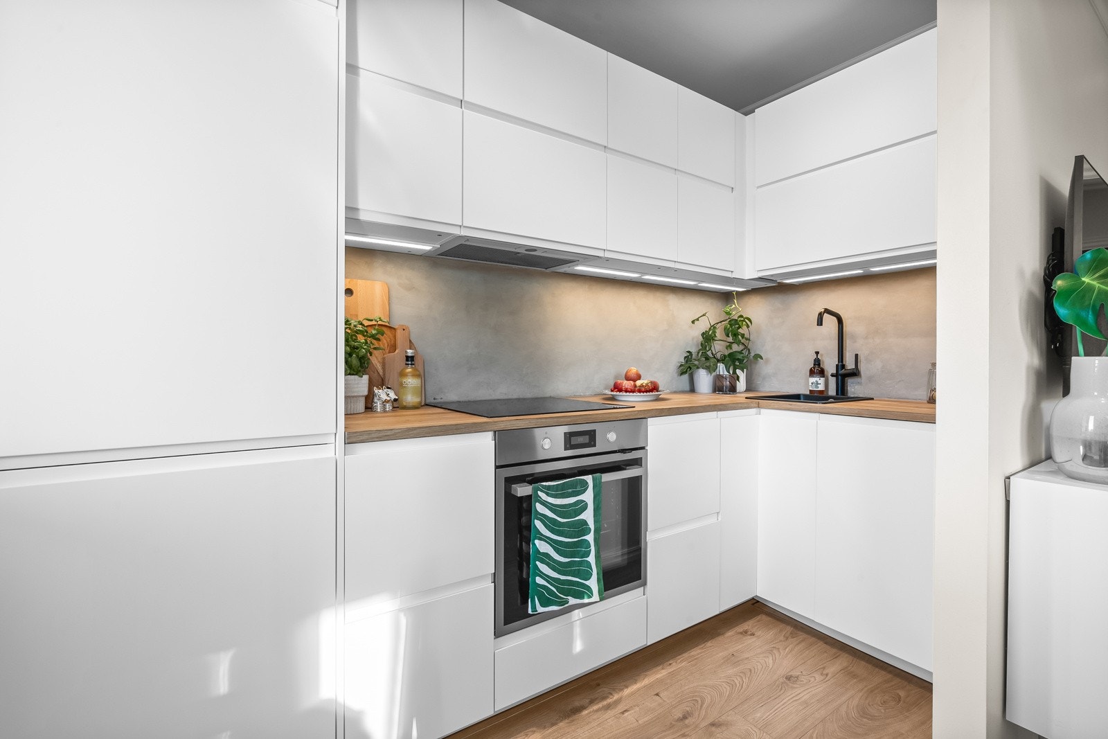 Pent og moderne IKEA-kjøkken fra 2022 med glatte, hvite fronter. Det er montert lys i skuffene som slår seg på når skuffen åpnes. En både stilig og praktisk detalj. Galleribilde