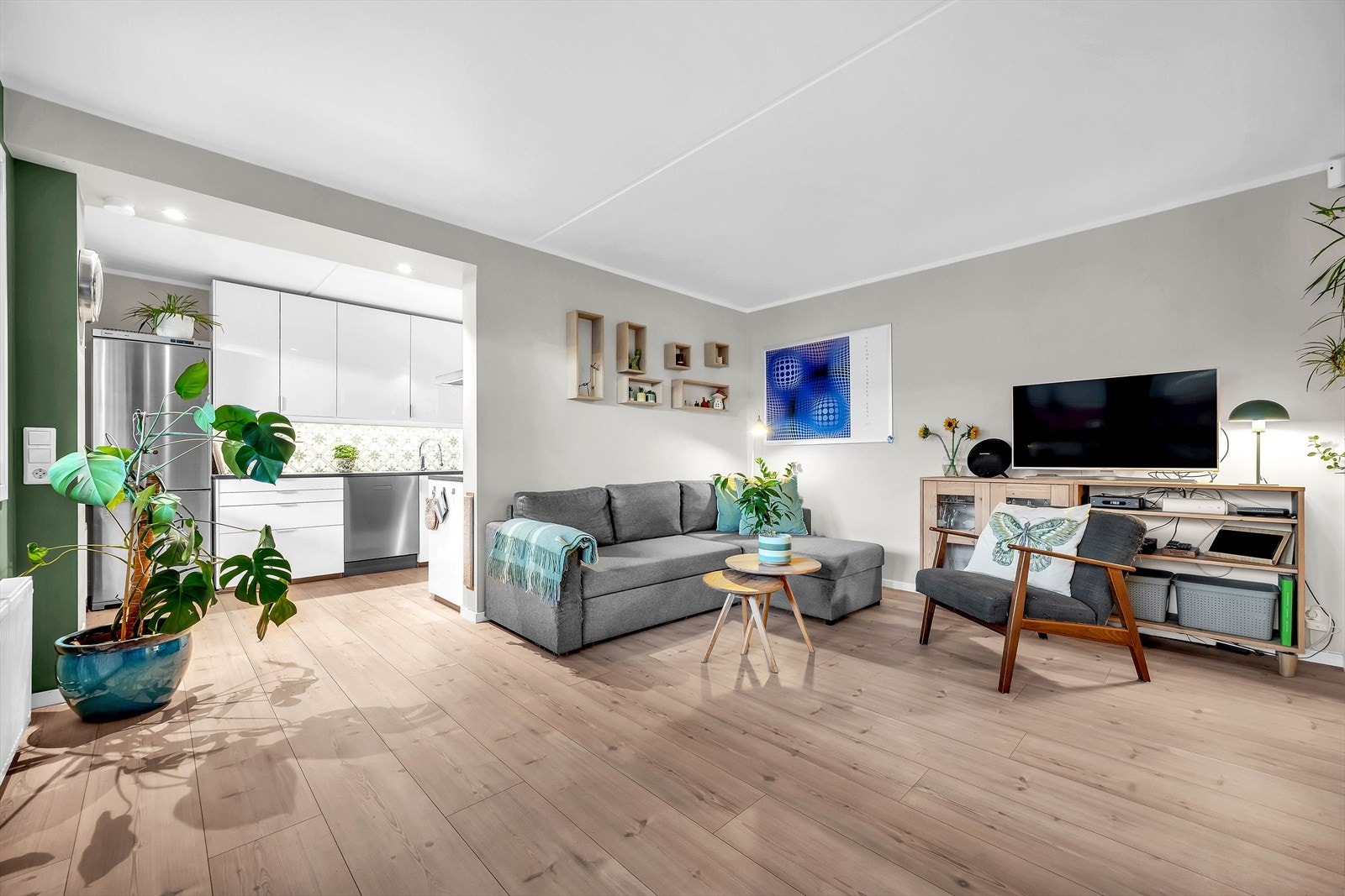 Leiligheten har en åpen stue og kjøkkenløsning som gir en sosial atmosfære med plass til flere sittegrupper. Galleribilde