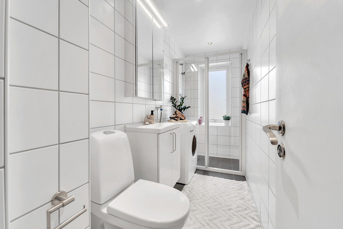 Pent og praktisk bad med dusj, toalett og tilkobling for vaskemaskin. Det er varmekabler i gulvet. Galleribilde