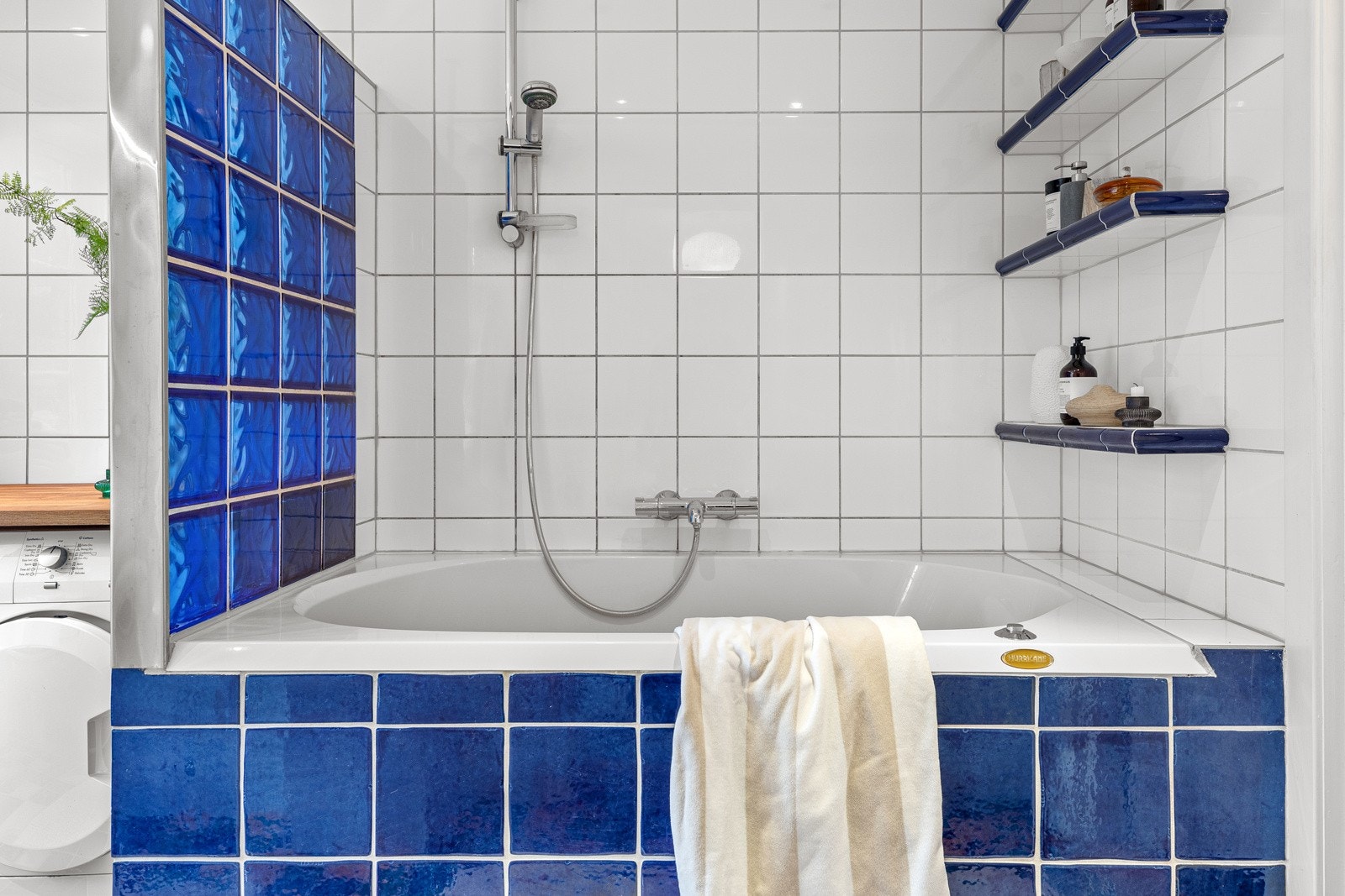 Innfliset baderkar med forheng og håndholdt dusjhode og håndkletørker Galleribilde