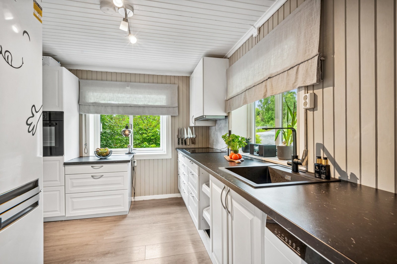 Kjøkken med moderne, praktisk innredning og integrerte hvitevarer. To vinduer gir godt med lysinnfall i rommet. Galleribilde