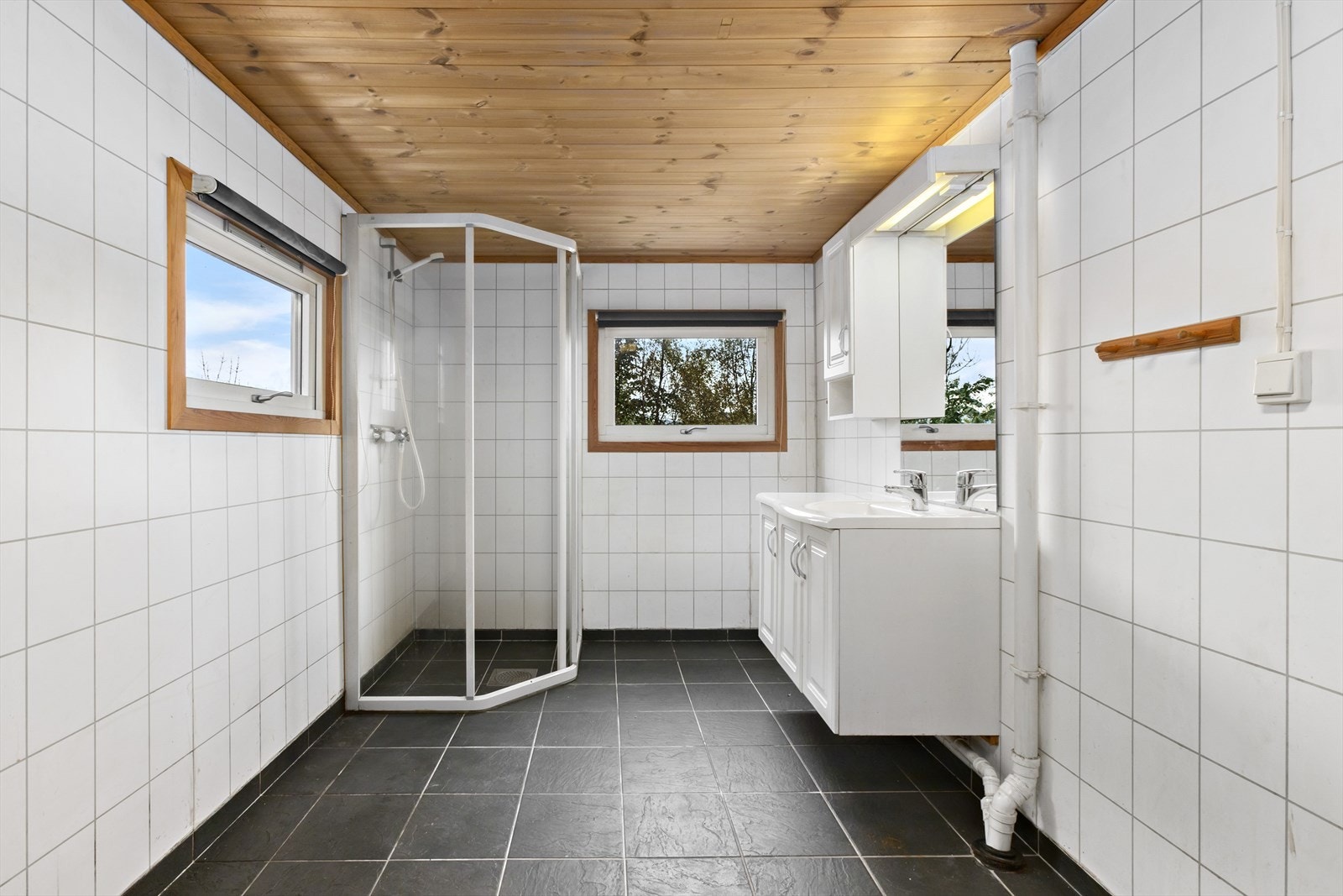 Badet er av god størrelse, med plass til vaskemaskin, dusjhjørne, møblement og toalett. Galleribilde