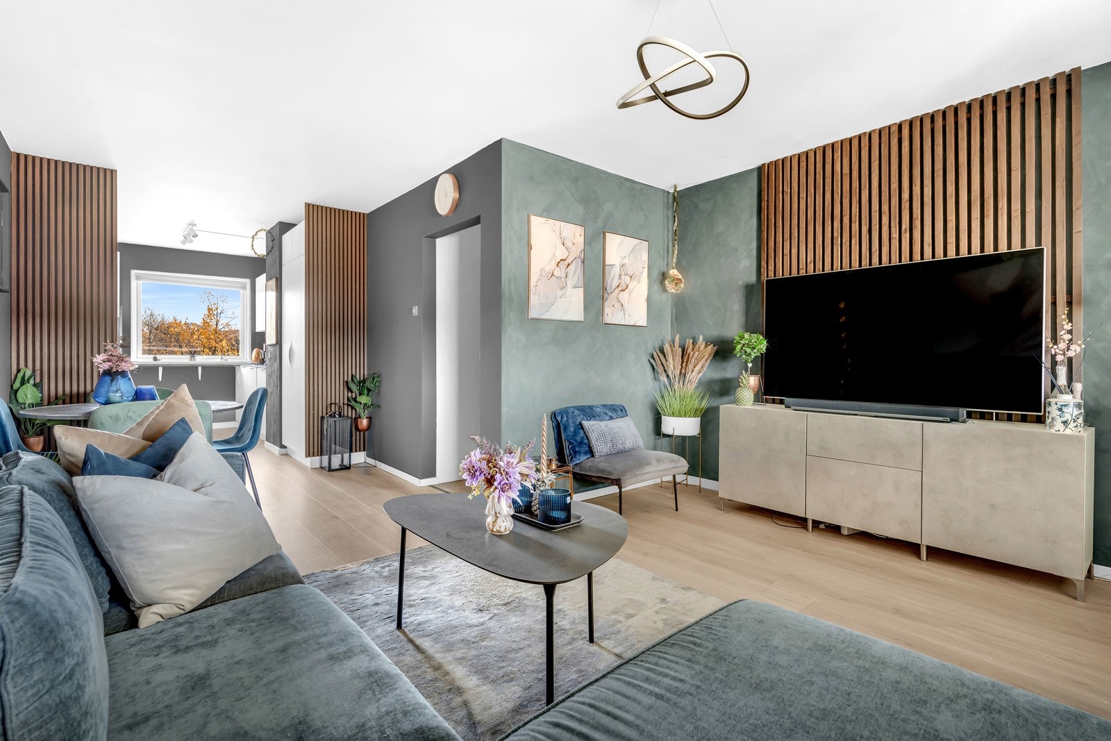 Den lyse stuen med store vinduer glir over i et moderne kjøkken med flotte hvitevarer Galleribilde