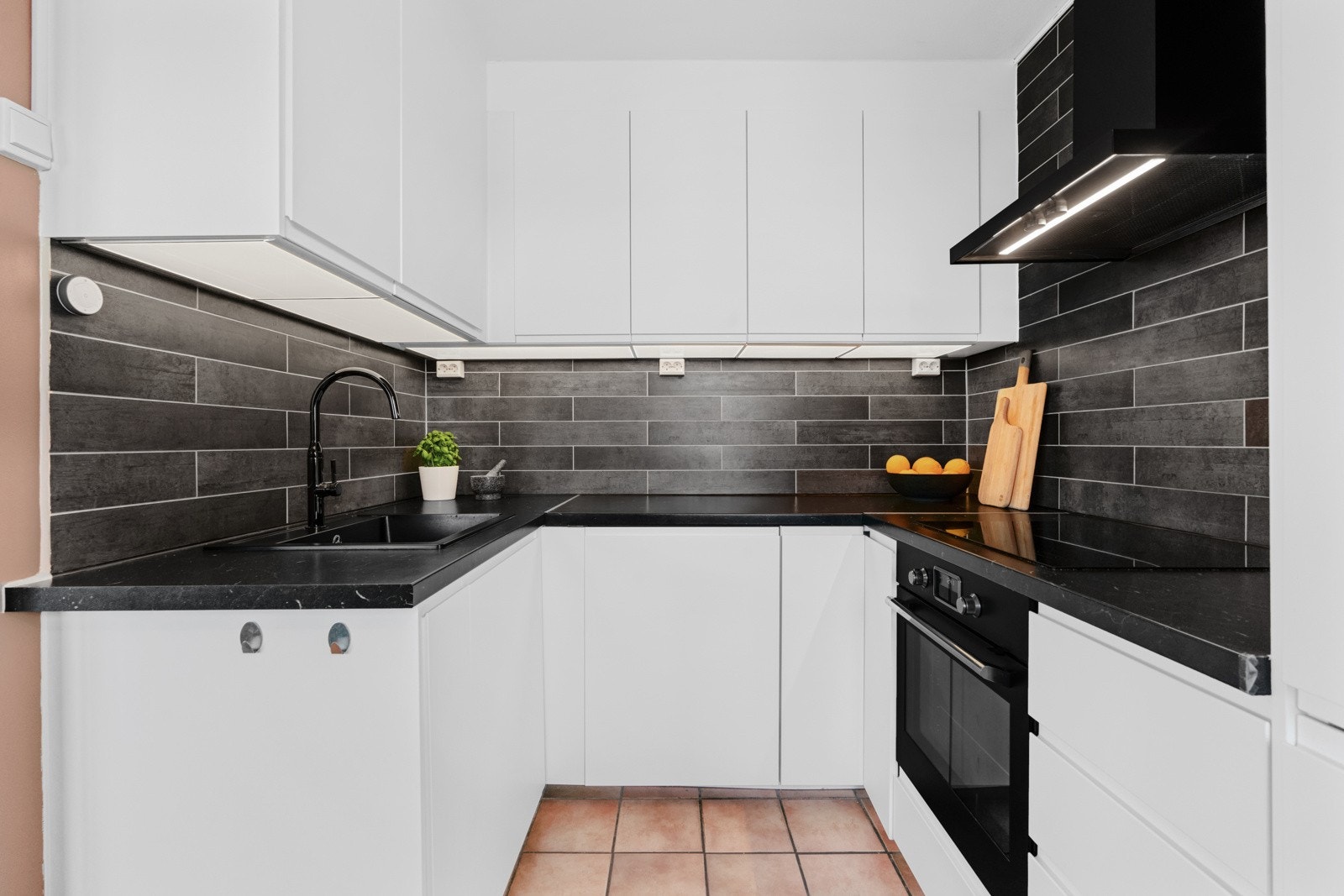 Kjøkkeninnredningen fra Ikea har slette fronter og dempefunksjon, laminat benkeplate med fliser over og enkel oppvaskkum. Galleribilde