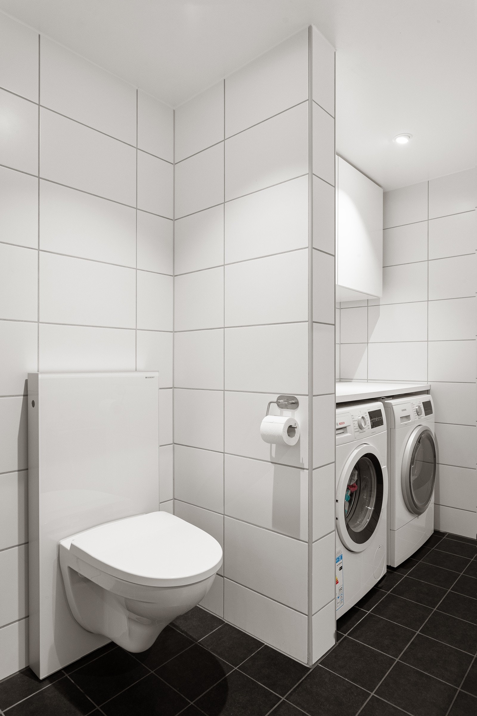 Praktisk med egen nisje med plass og opplegg for både vaskemaskin og tørketrommel under benkeplate, samt god oppbevaringsplass i vegghengte skap over. Avtrekksventil i himling tilkoblet balansert ventilasjon. Galleribilde