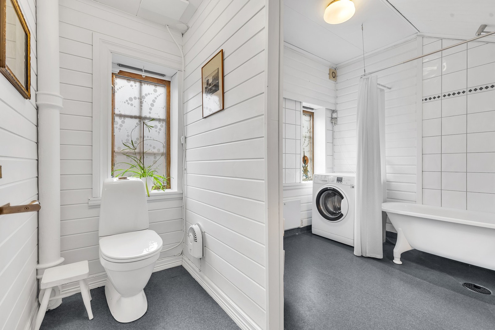 Leilighetens bad er utstyrt med badekar med dusjbatteri og dusjforheng montert på vegg, gulvmontert toalett samt kran og avløp for vaskemaskin. Galleribilde