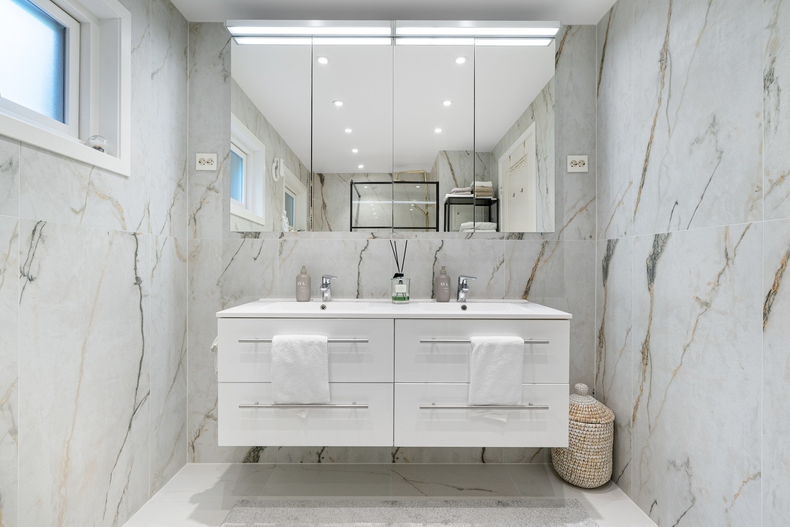 Delikat flislagt baderom utstyrt med dobbel vask i seksjon, vegghengt toalett og dusj Galleribilde