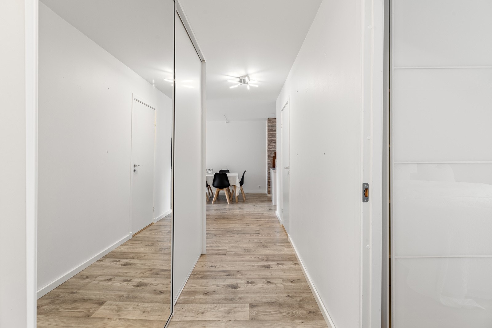 Romslig entré som gir et godt førsteinntrykk av boligen. Her er det rikelig med oppbevaringsplass i en stor skyvedørsgarderobe med speilfronter Galleribilde