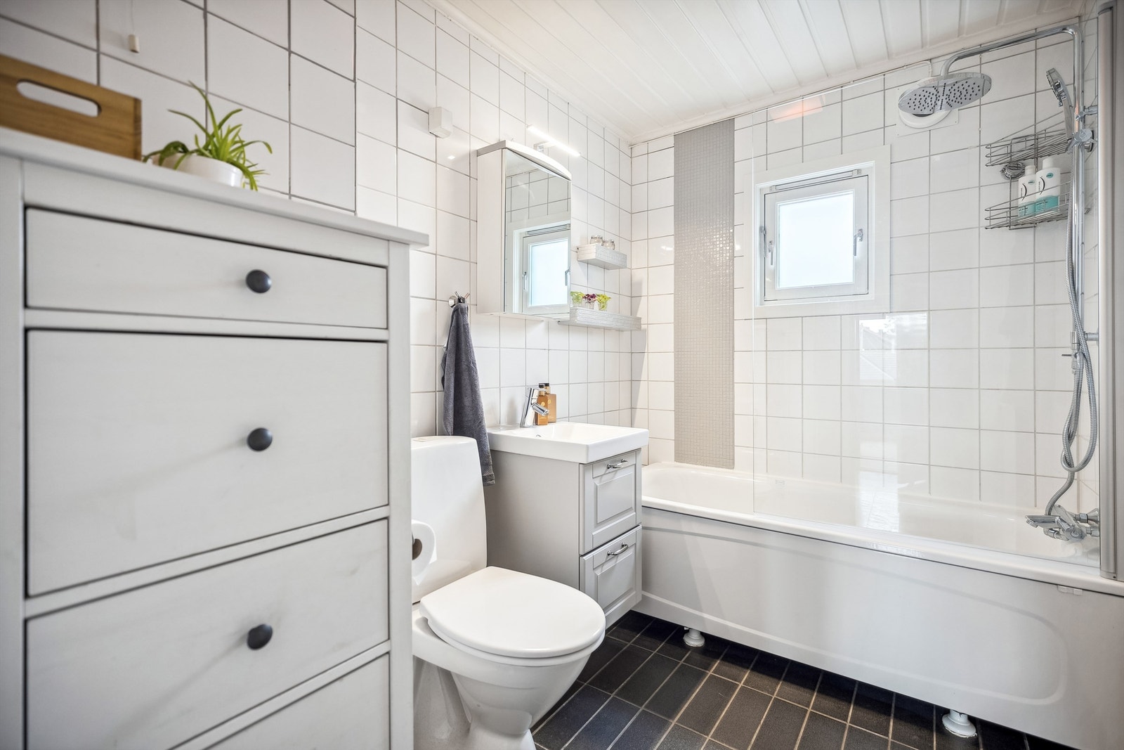 Flislagt bad med gulvvarme og himling av malt panel. Badet er modernisert. Vindu, badekar, dusjevegg og vifte på vegg, samt nyere innredning. Galleribilde