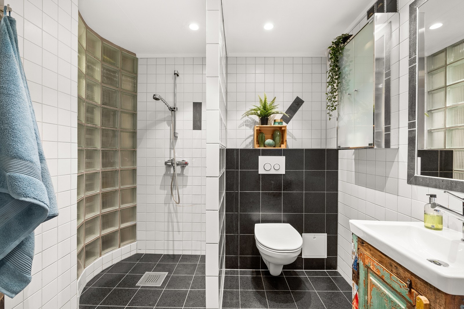 Kjeller har flislagt bad med varmekabler, dusj, veggfestet toalett og servant med speil Galleribilde