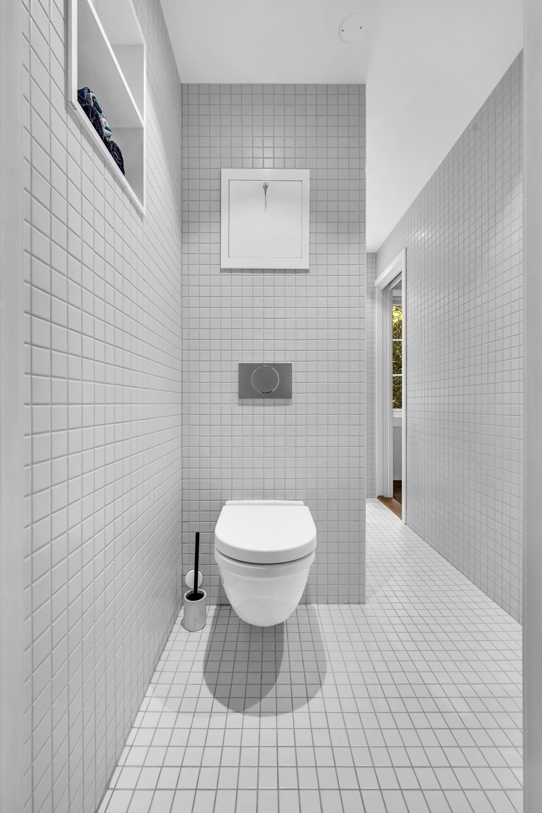 Baderommet inneholder veggmontert toalett, dusjnisje med innfellbar glassdør og servantskap med servant, speil og belysning. Galleribilde