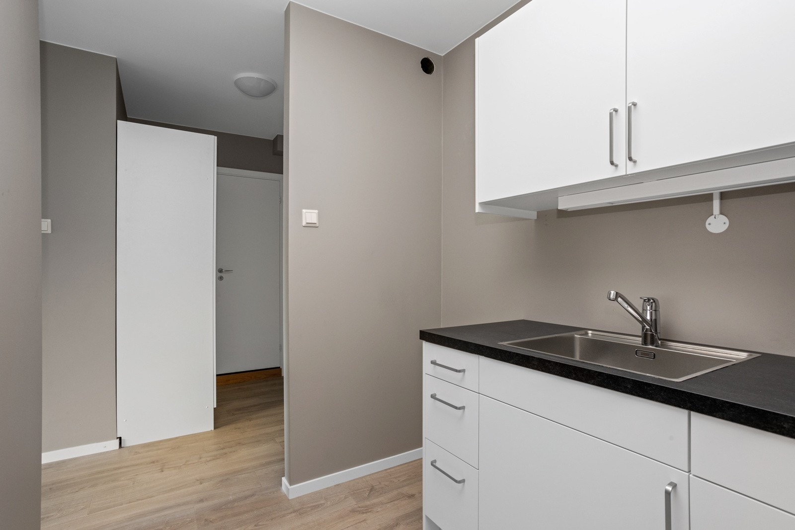 Her ser vi mot gangen med garderobeskap og badet innenfor døren innerst. Galleribilde