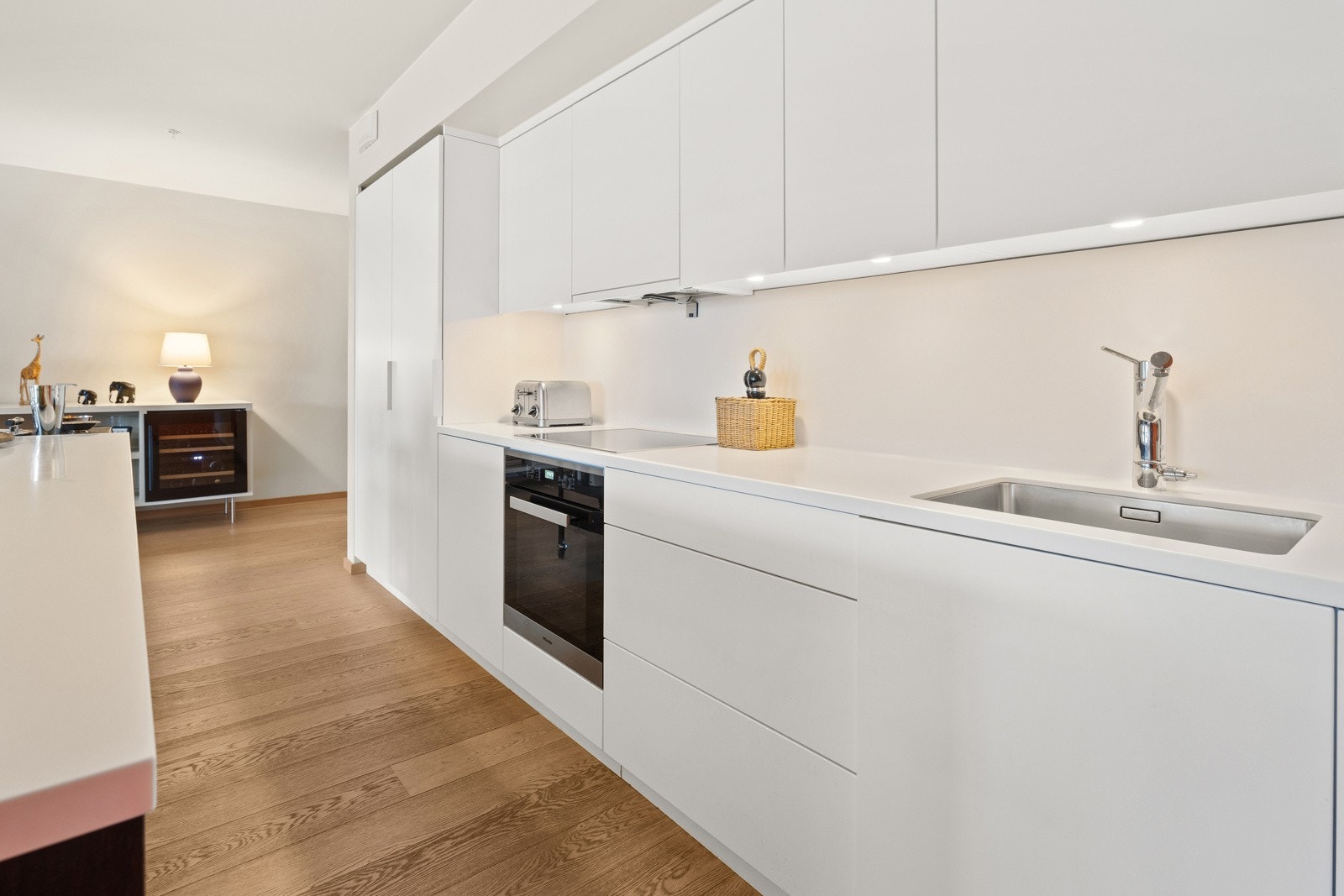 Kjøkkenet er innredet med glatte fronter, Korian benkeplate, ventilator, underlimt oppvaskkum, øy med popup el.stikk og integrerte hvitevarer Galleribilde