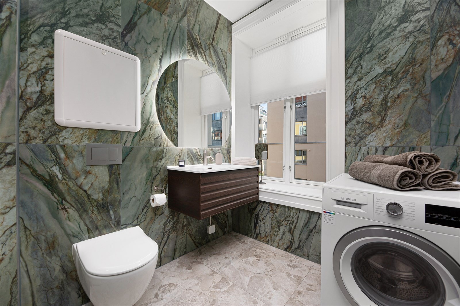 Benkeskap med profilerte fronter og speil over servant og vegghengt toalett- Opplegg for vaskemaskin Galleribilde