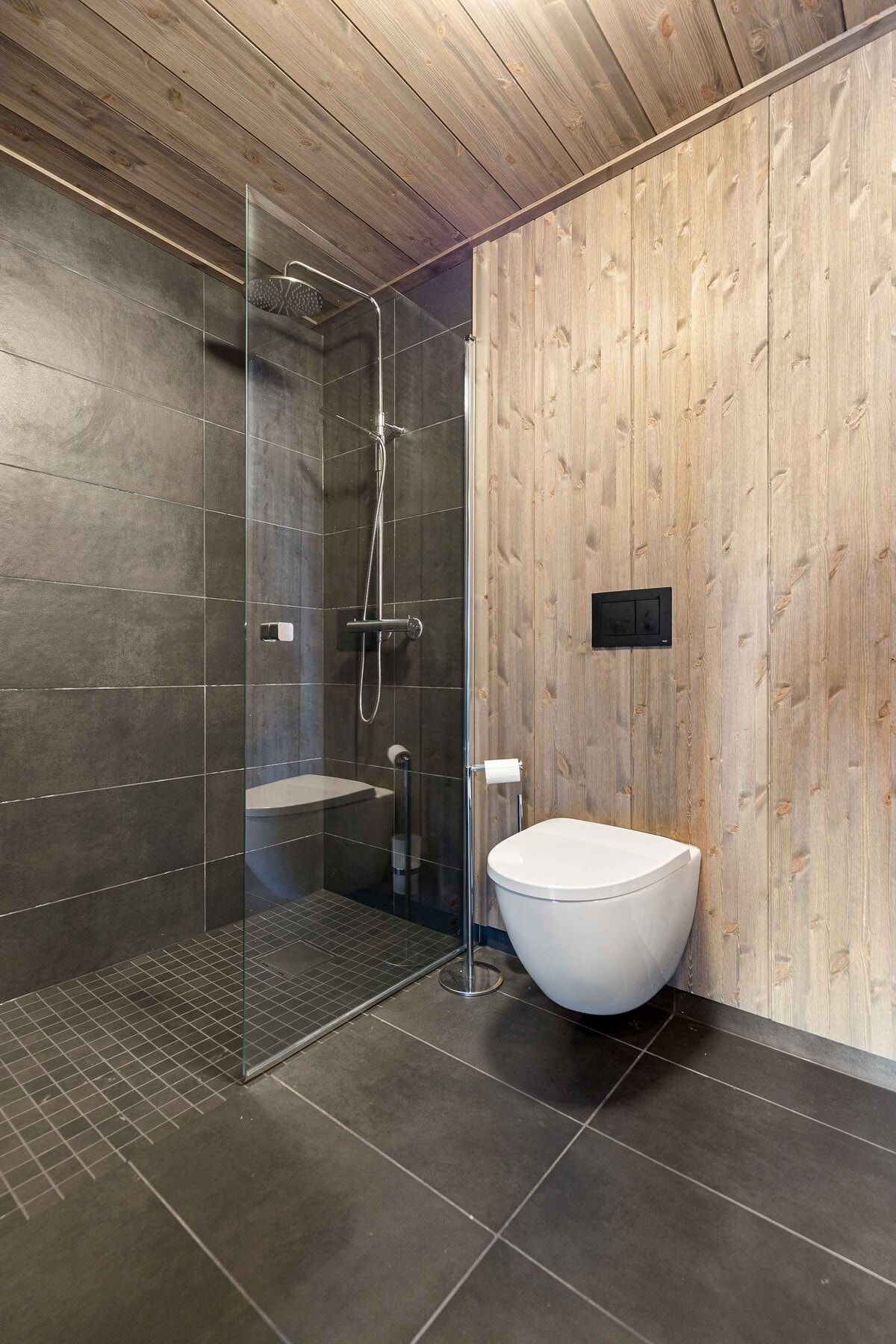 Bad har flislagt gulv og dusjnisje. Heltre Vy-panel på vegger.
Foto fra ett av badene i vår visningshytte på feltet Galleribilde